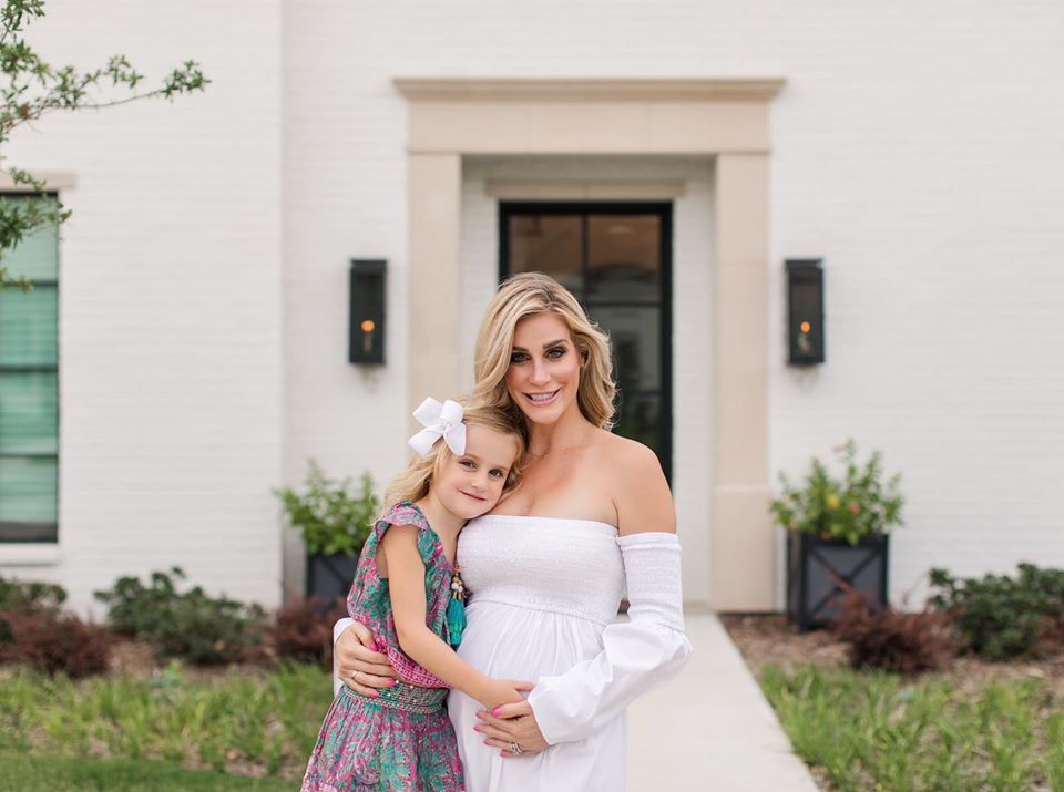 Pregnant women wearing a white dress with daughter posing for maternity photos