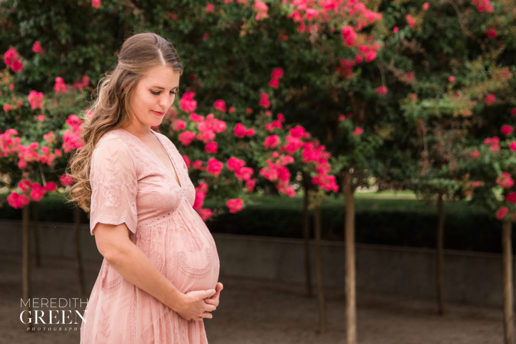 posing for maternity photos woman in pink dress holding her belly