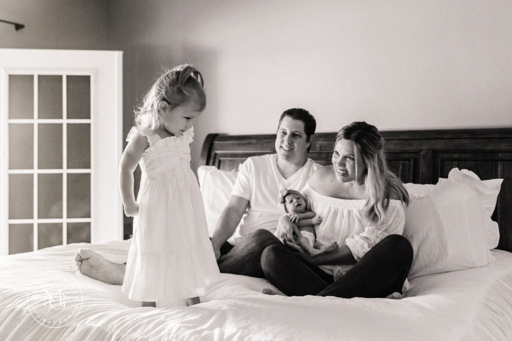family sitting on bed during newborn lifestyle session