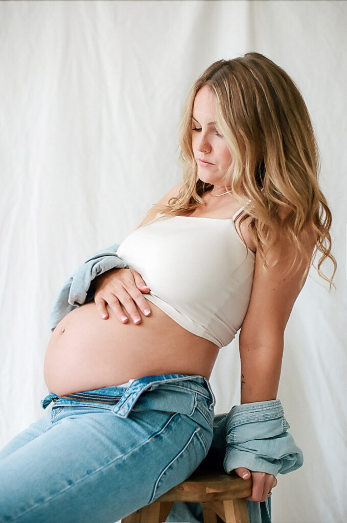 Mother sitting on stool posing at maternity photo session