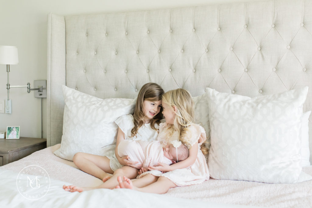Sisters holding baby sister at in home newborn session