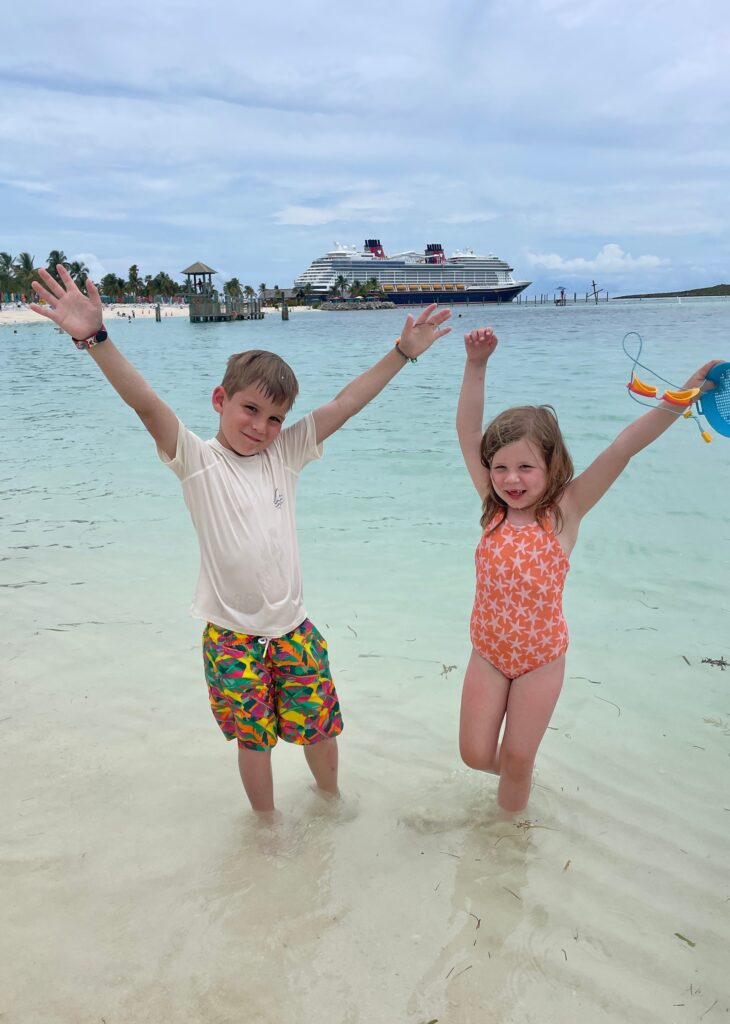 kids on beach in front of Disney Cruise ship