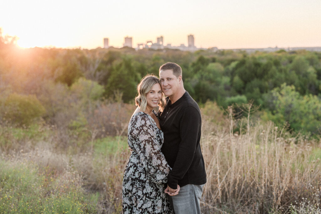 Mr. and Mrs. Burch holding hands in front of Fort Worth skyline during fall family photos.