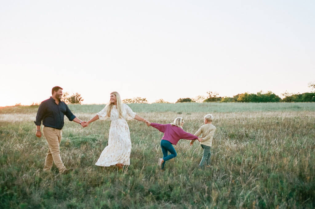 Morford family holding hands walking through a field for fall family photos