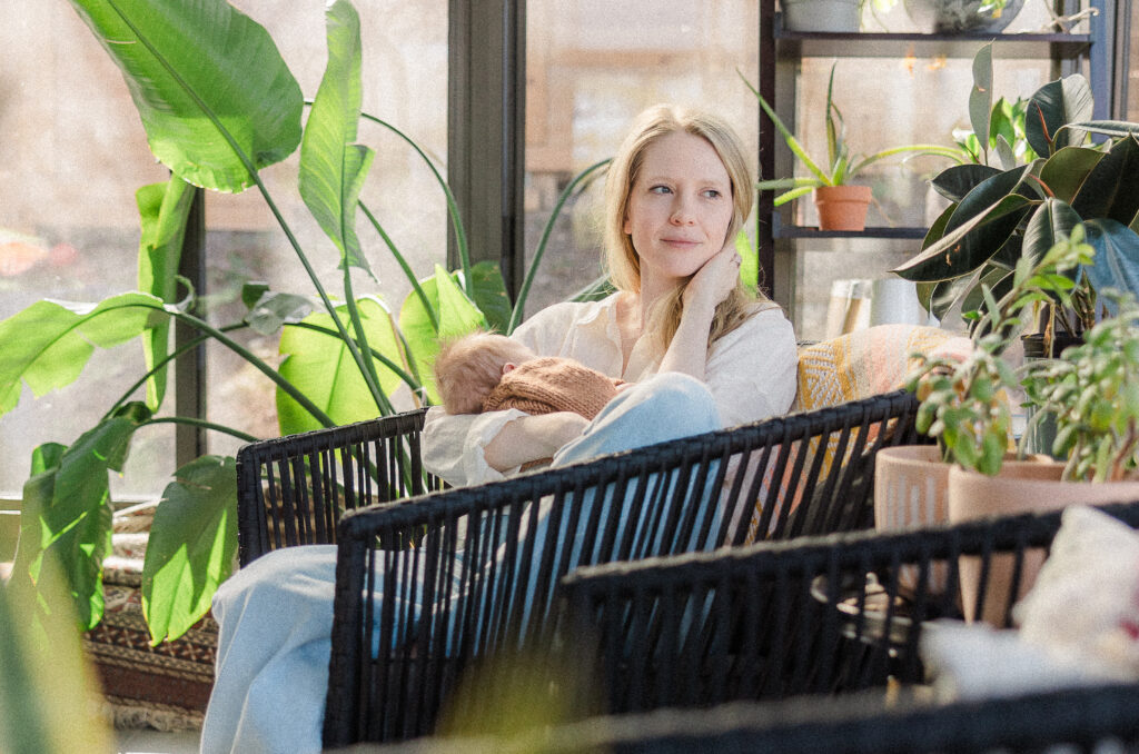 Sonny and his mother sitting in greenhouse during newborn photos